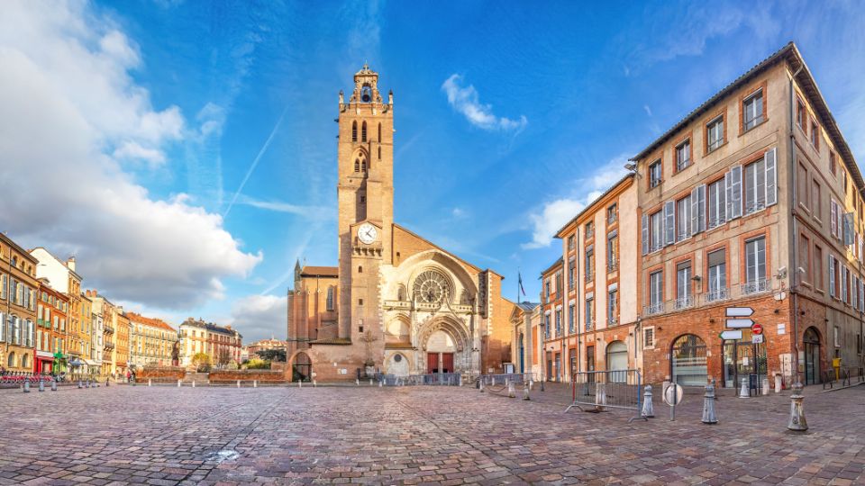 Panorama de la place et de la Cathédrale Saint-Étienne à Toulouse sous un ciel bleu.