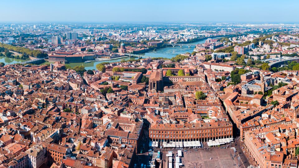 Vue aérienne de la ville de Toulouse, montrant les toits rouges et la rivière traversant la ville.