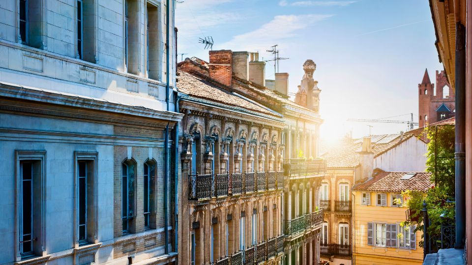 Façades d'immeubles anciens dans une rue ensoleillée de Toulouse