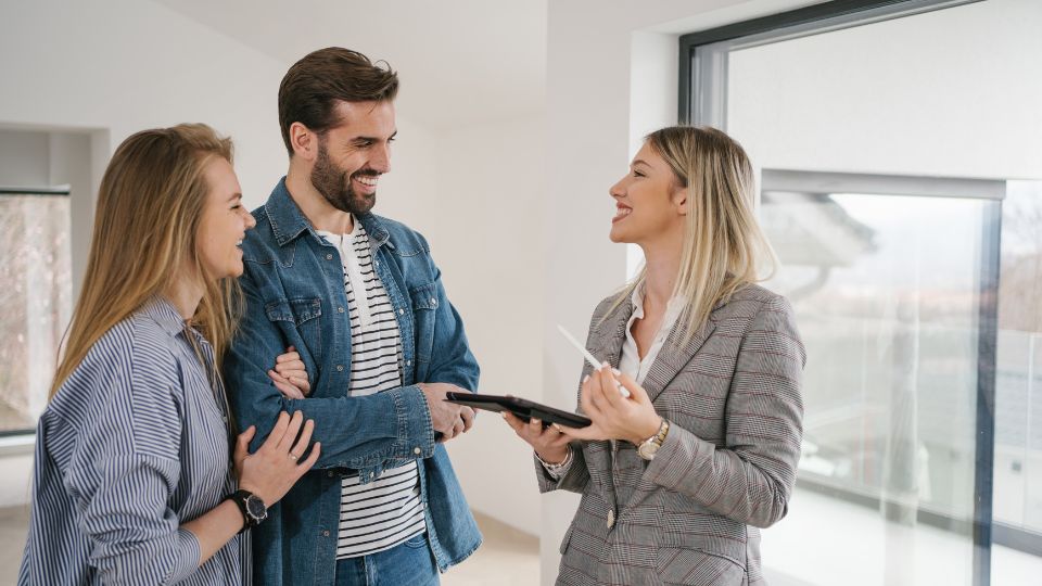 Un couple discutant avec une agent immobilier à l'intérieur d'une maison